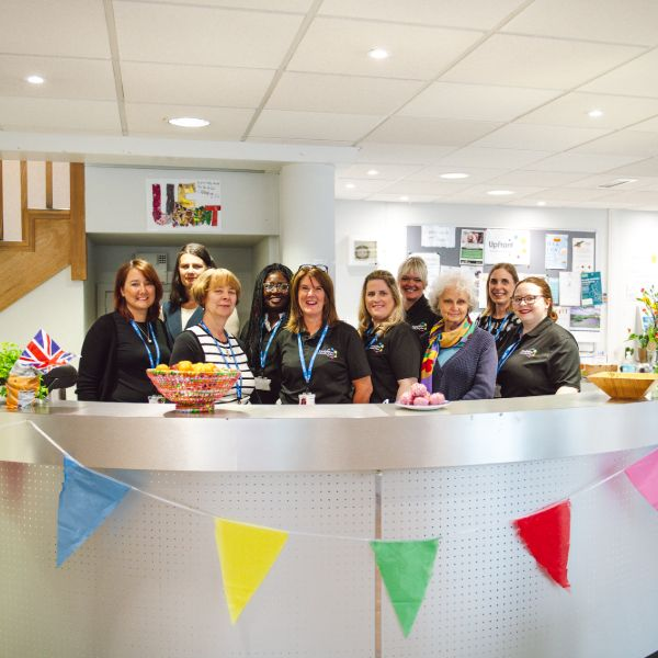 female staff members stood behind a desk smiling